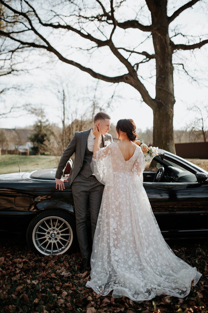 A Man in Gray Suit and a Woman in White Dress Standing Near the Car in the Park